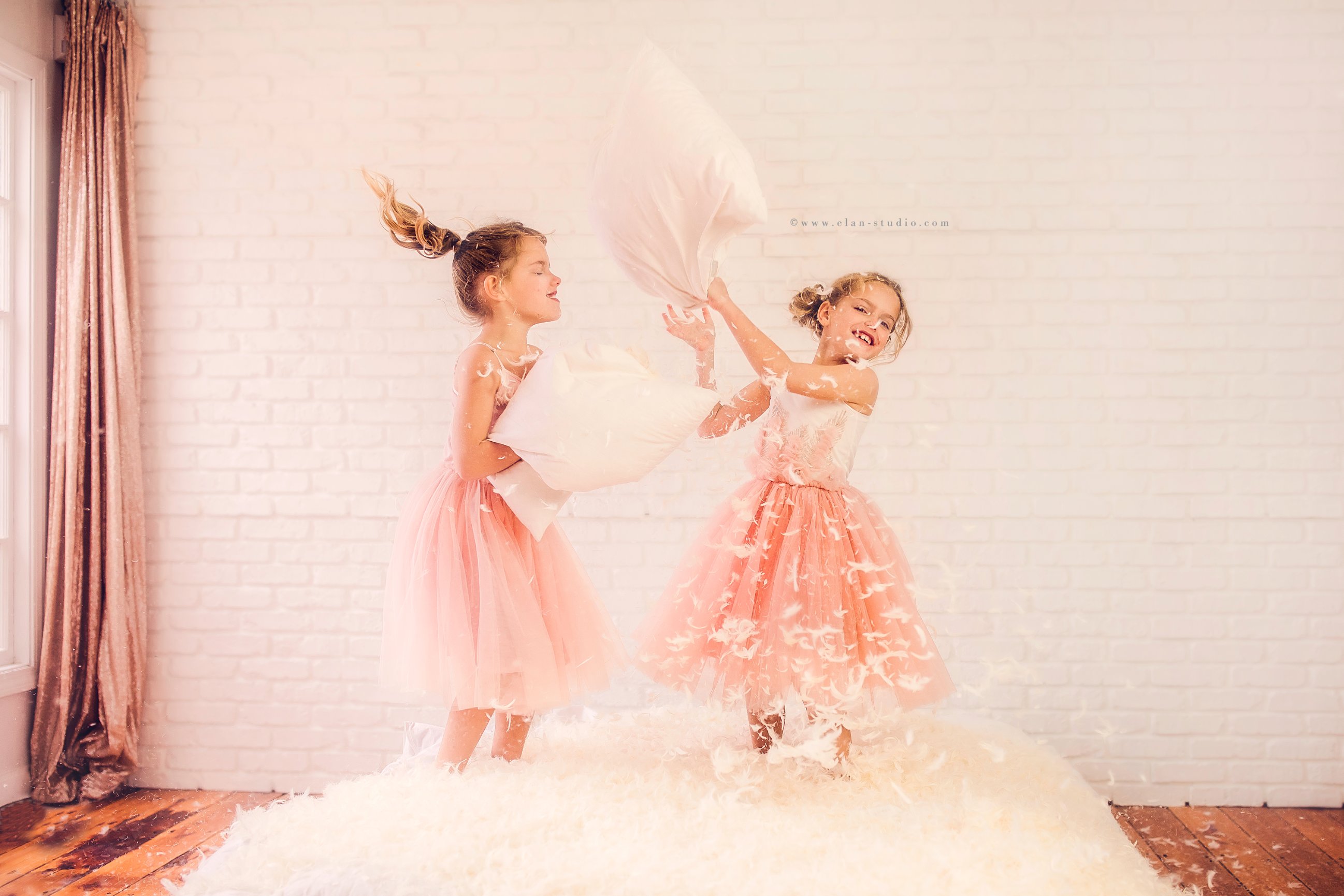 little girls having pillow fight in photography studio