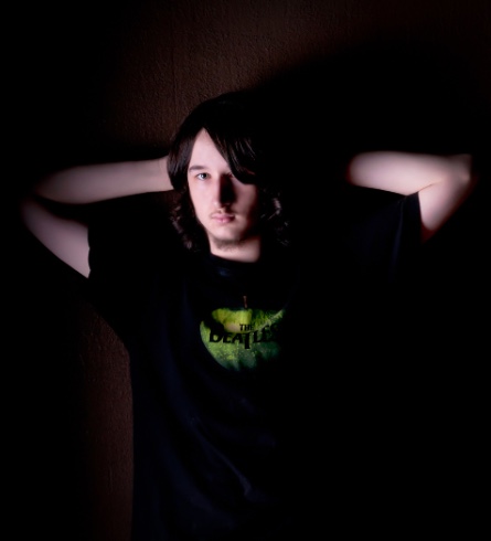 graduating senior boy posing for senior pictures in studio on black background