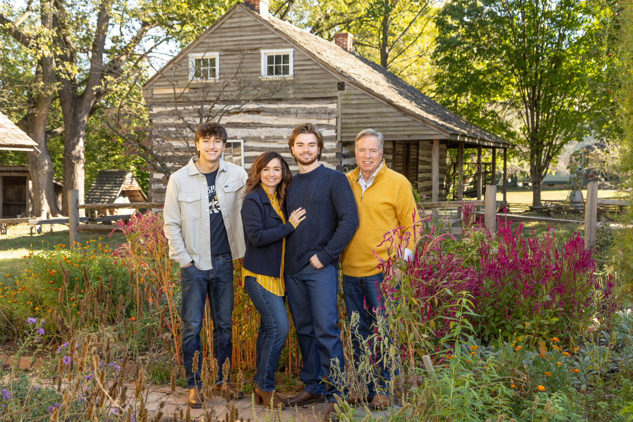 Family posing by rustic cabin
