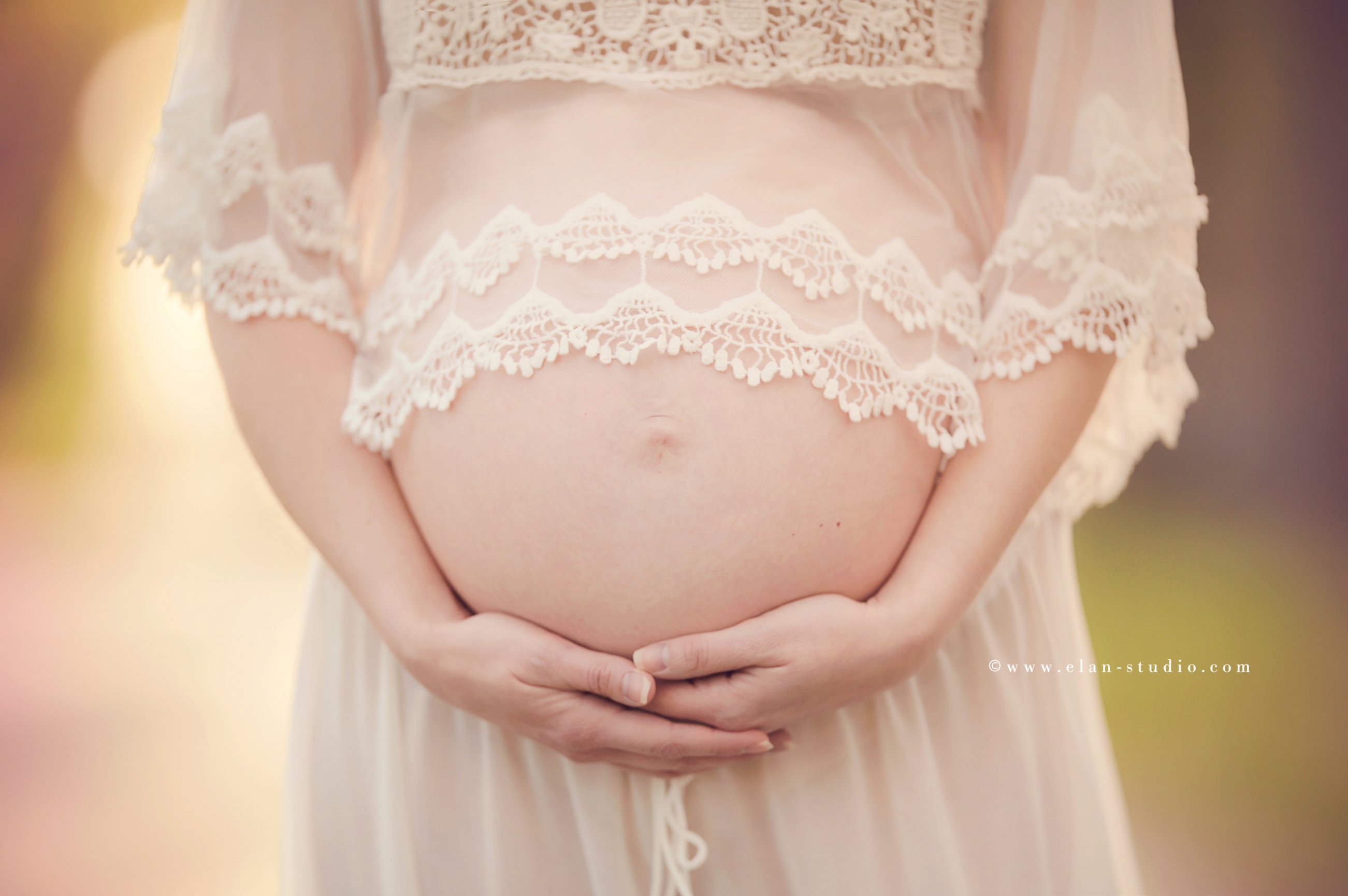 mother wearing lace top, holding pregnant belly