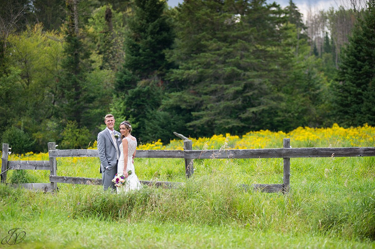 bride and groom near fence lake placid yellow flowers