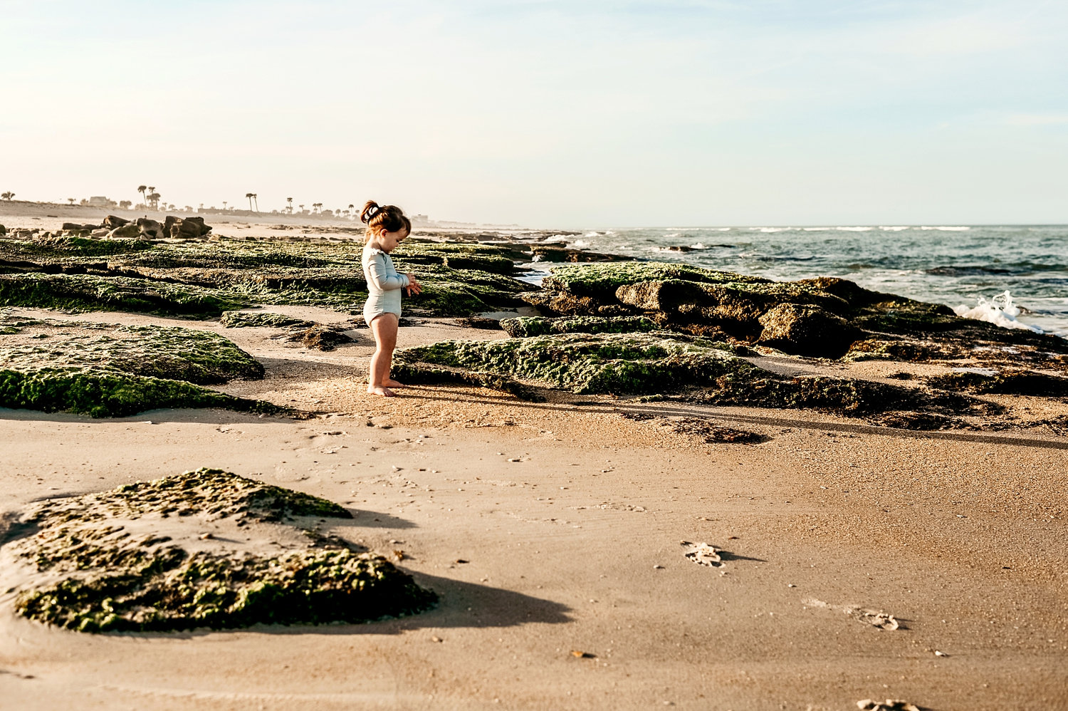 toddler girl among moss covered rocks at the beach, Florida, Ryaphotos