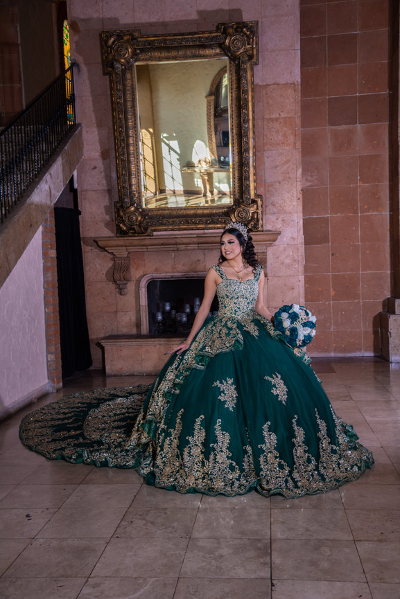 Young woman in ornate green gown indoors