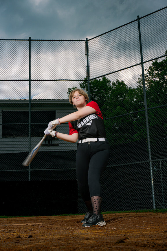 girl swinging a softball bat on the softball field