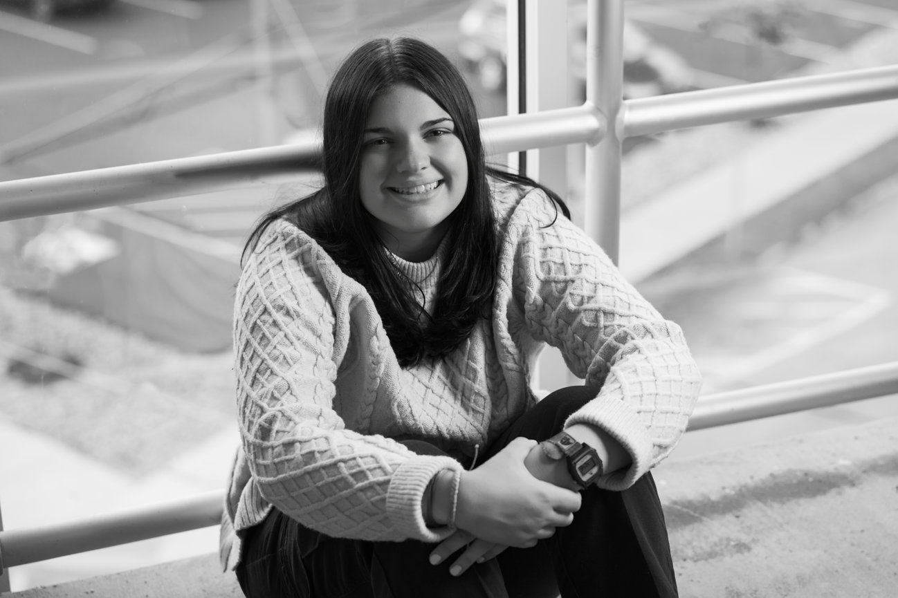black and white portrait of a senior girl in a casual outfit while sitting in a parking garage in grove city pa