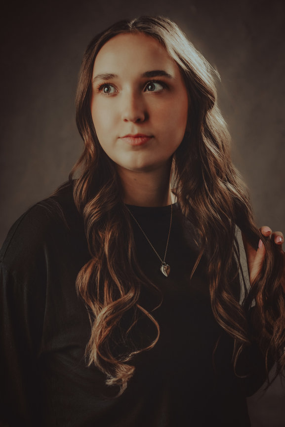 Close up portrait of young woman in studio with warm elements and black sweater, taken in a photo studio with Adam Trujillo, a Las Vegas portrait photographer.