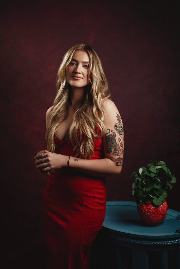 Elegamt studio portrait by Adam Trujillo with woman in red dress, blonde hair and crimson red handpainted backdrop, taken in a photo studio with Adam Trujillo, a Las Vegas portrait photographer.