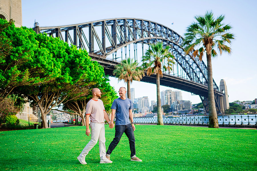 A photoshoot with a romantic couple walking in a park near the Sydney Harbour Bridge.