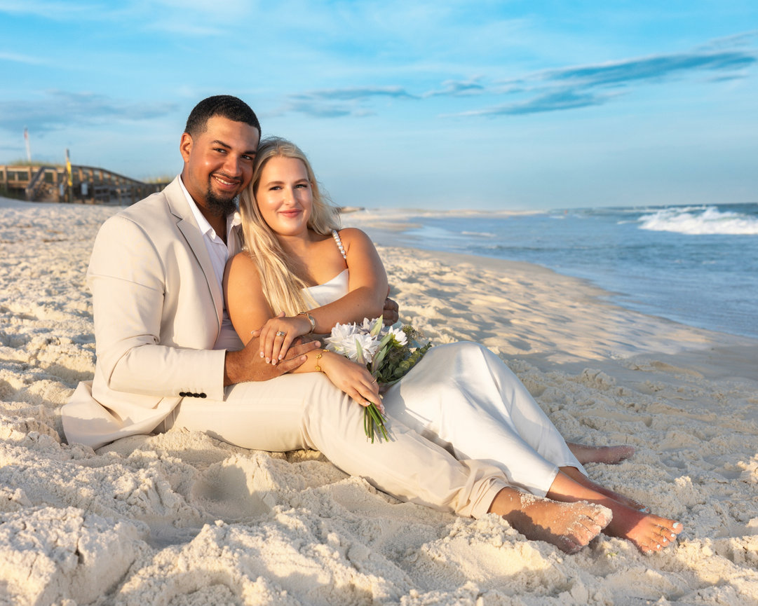 Couple seated on the sand at sunset during their romantic Gulf Coast elopement session, photographed by Dixon Creative Images.