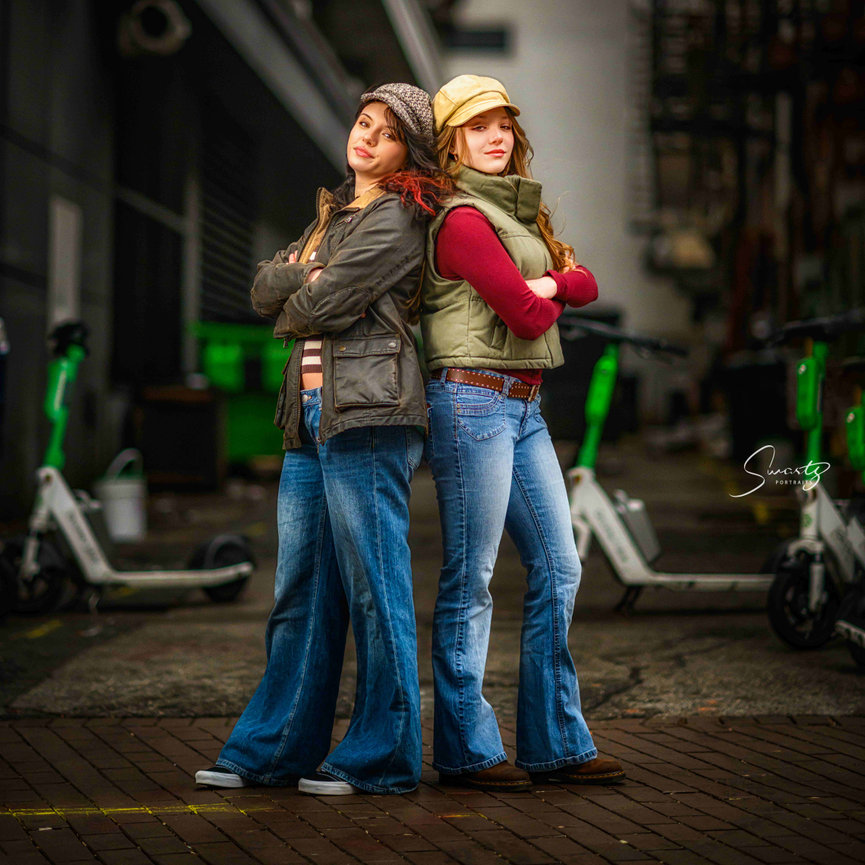Sisters in stylish outfits posing in downtown urban environment