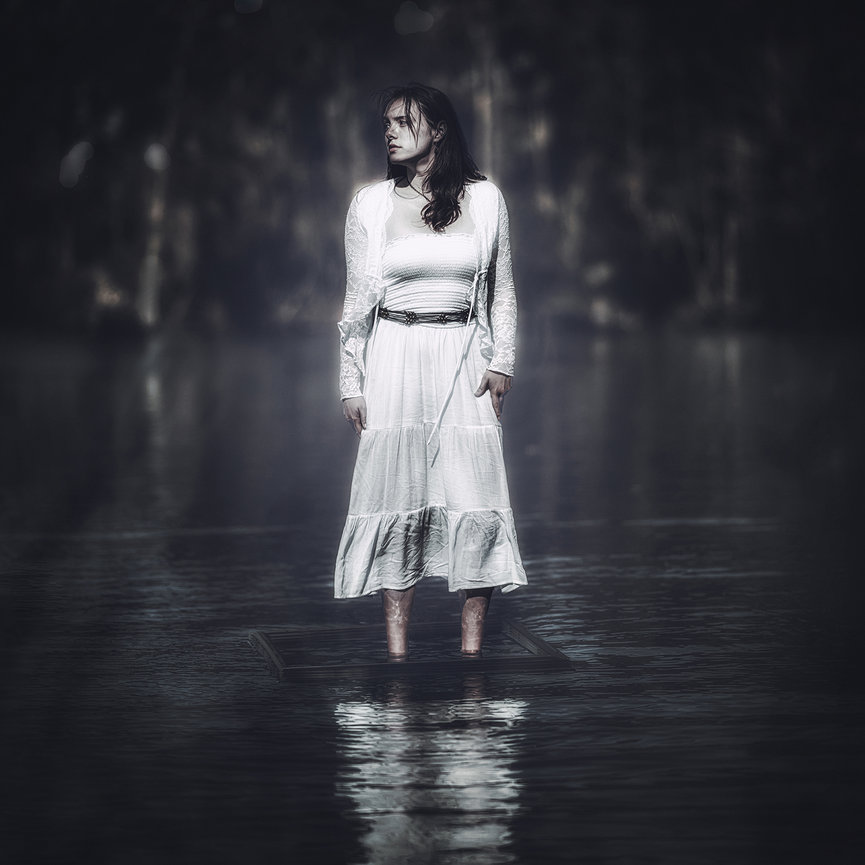Ethereal senior portrait of girl barefoot in white peasant dress standing in still lake reflection at dusk, surreal master-level fine art editorial photography by Ty Swartz, Swartz Portraits Spring Texas serving The Woodlands and Conroe