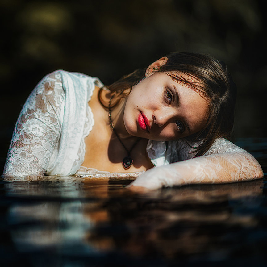 Conceptual fine art senior portrait, face partially submerged in water reflection wearing white lace, master-level editorial photography by Ty Swartz, Swartz Portraits Spring Texas senior portrait experience