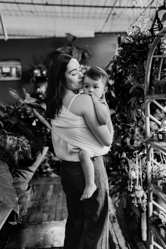 Woman holding baby in baby carrier in Huntsville Alabama greenhouse