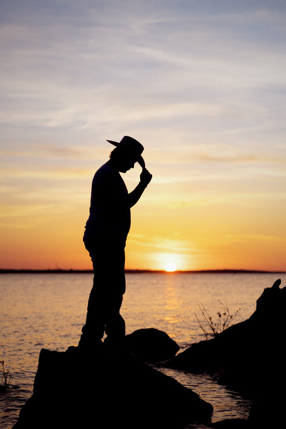 Senior picture guy at sunset wearing a cowboy hat, silhouette.
