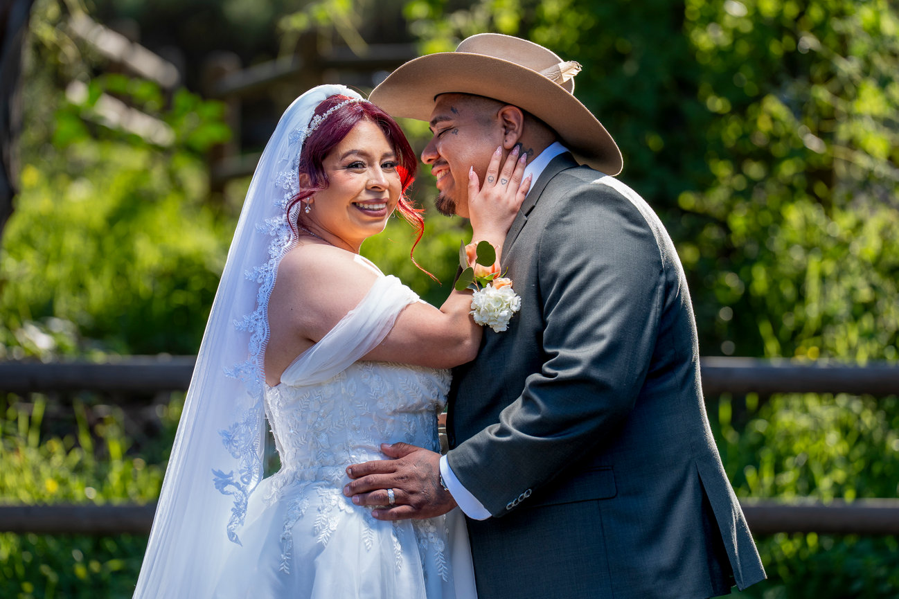 Bride and groom with cowboy hat in a rustic setting