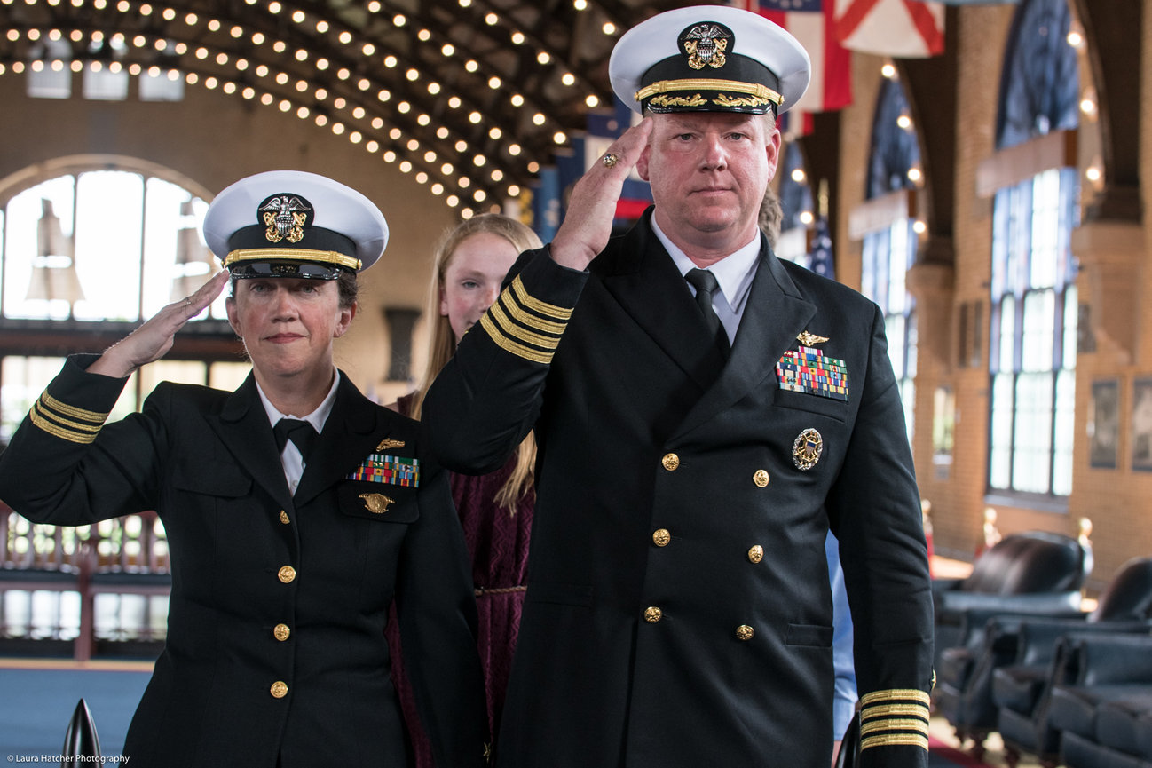 A husband and wife saluting at their dual naval retirement ceremony