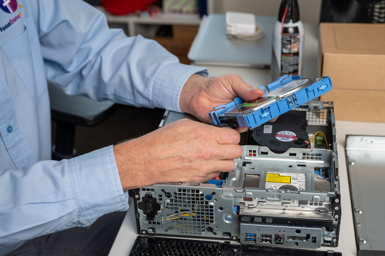 Technician installing a hard drive into an open desktop computer case