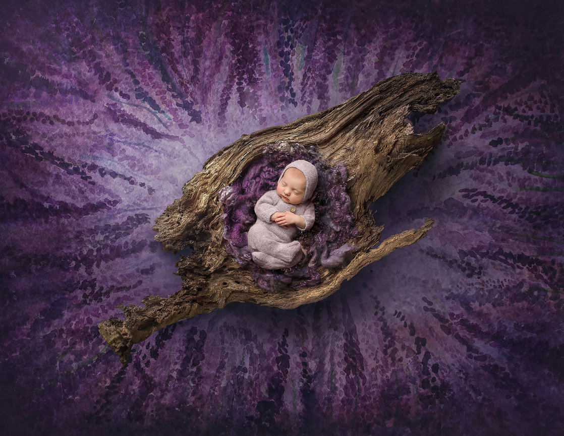 Newborn baby sleeping peacefully on a textured wooden piece with purple background.