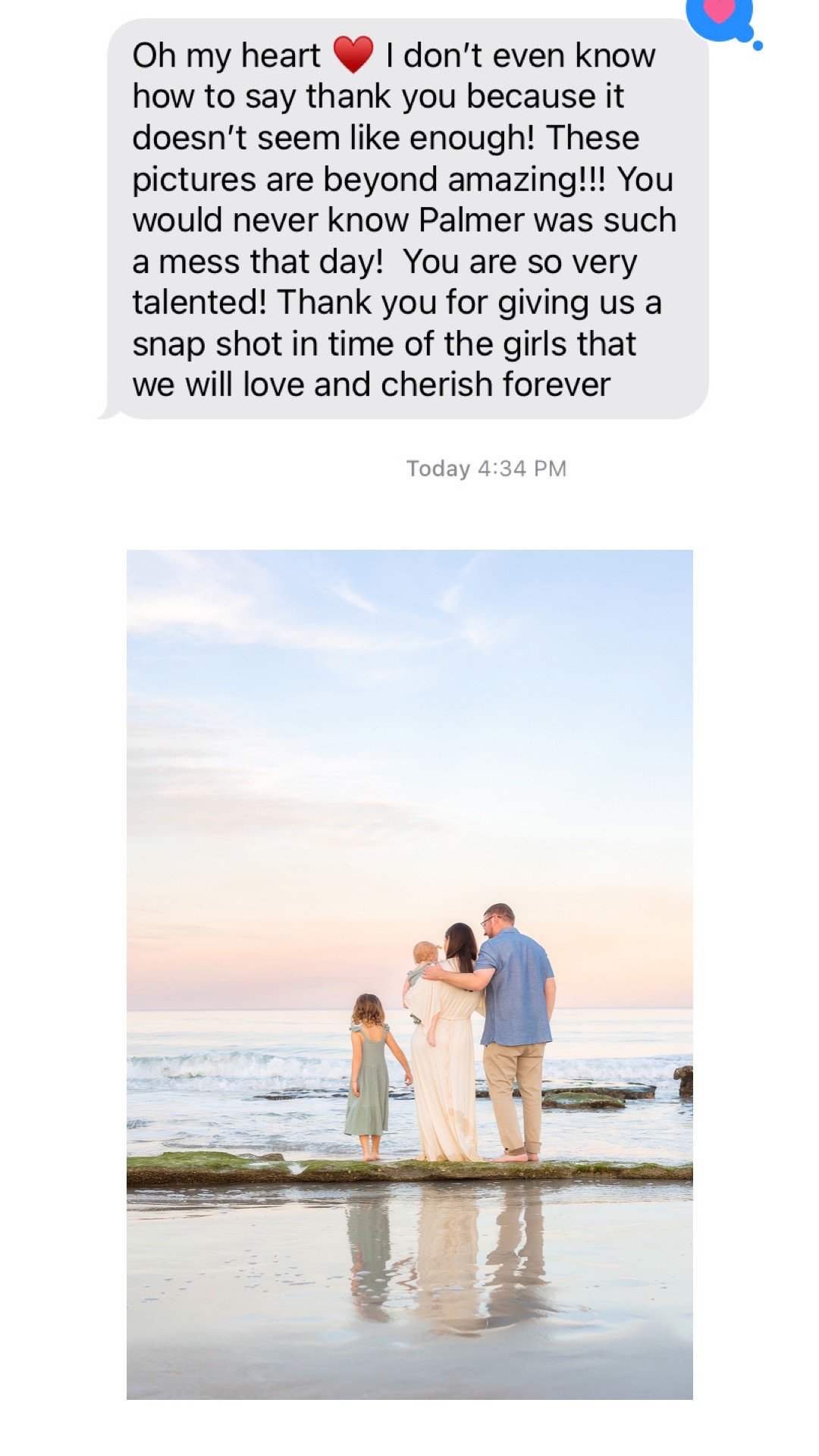 family standing at the beach in the water during sunset with pastel skies