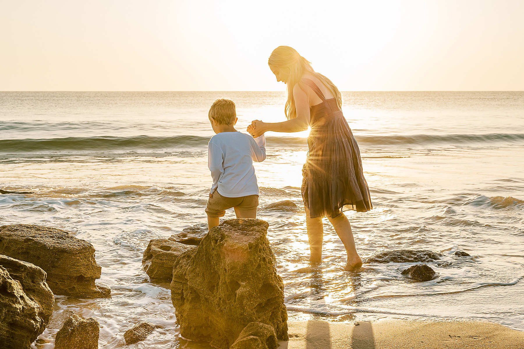 a light and airy sunrise family portrait of a woman and her son on the beach