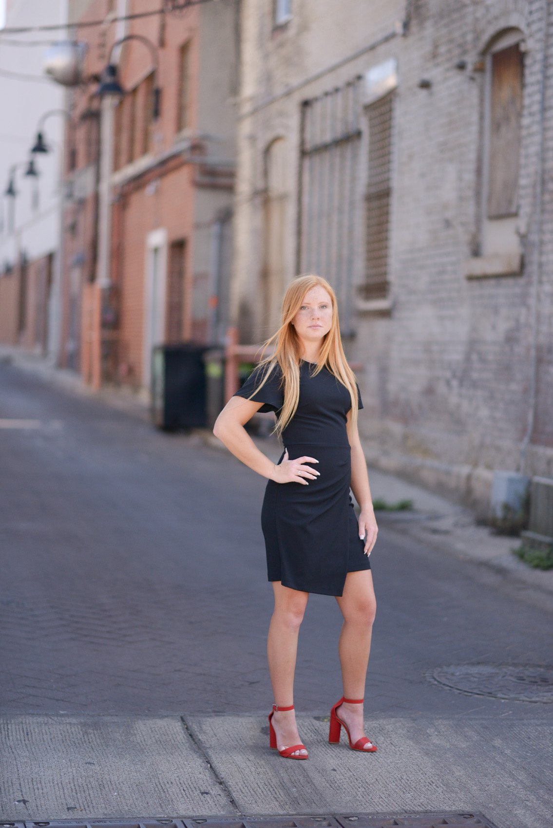 Senior girl in black dress standing on the sidewalk in front of the Holland Building in Springfield, Missouri.
