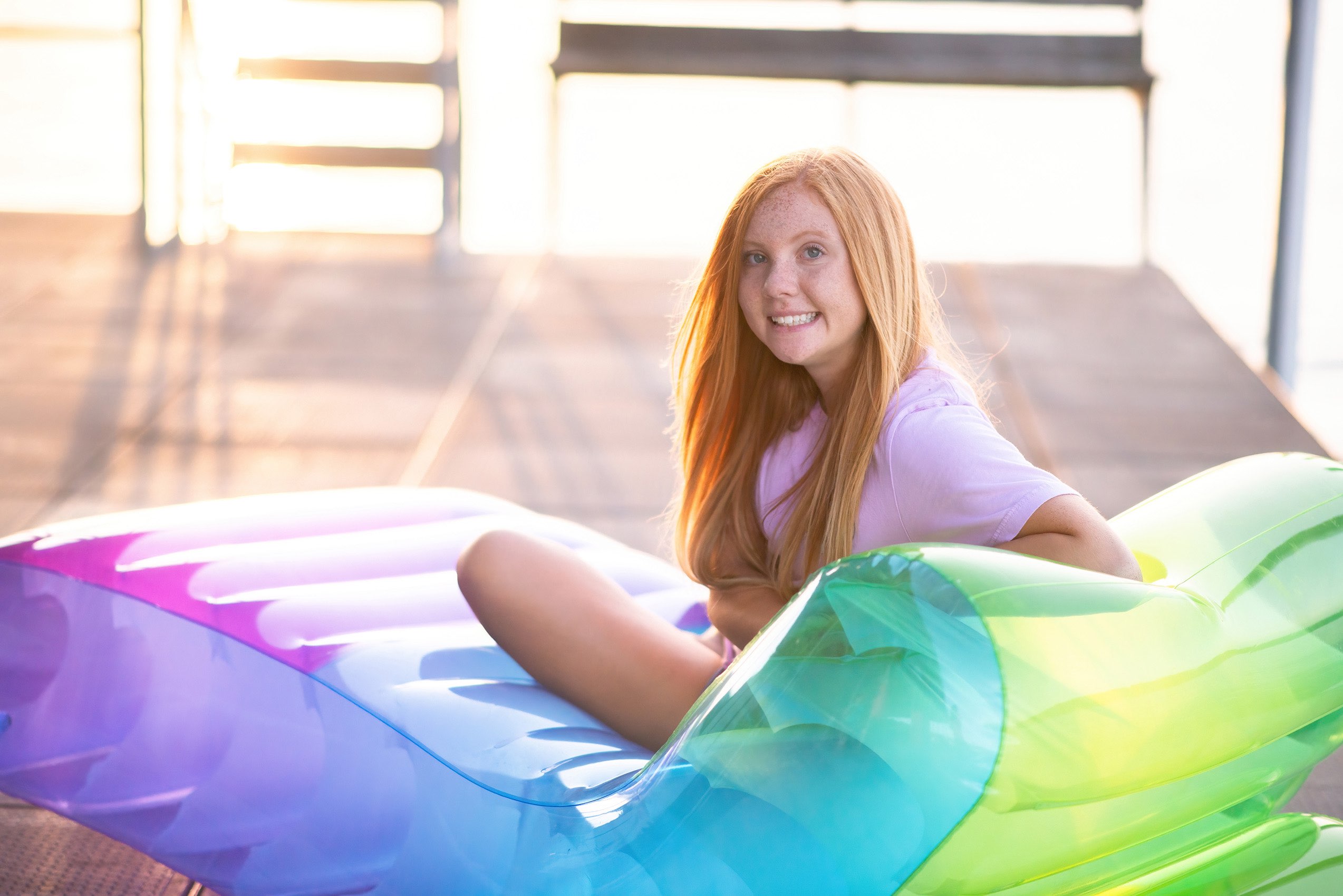 Senior girl sitting on rainbow lounge chair at Tablerock Lake.