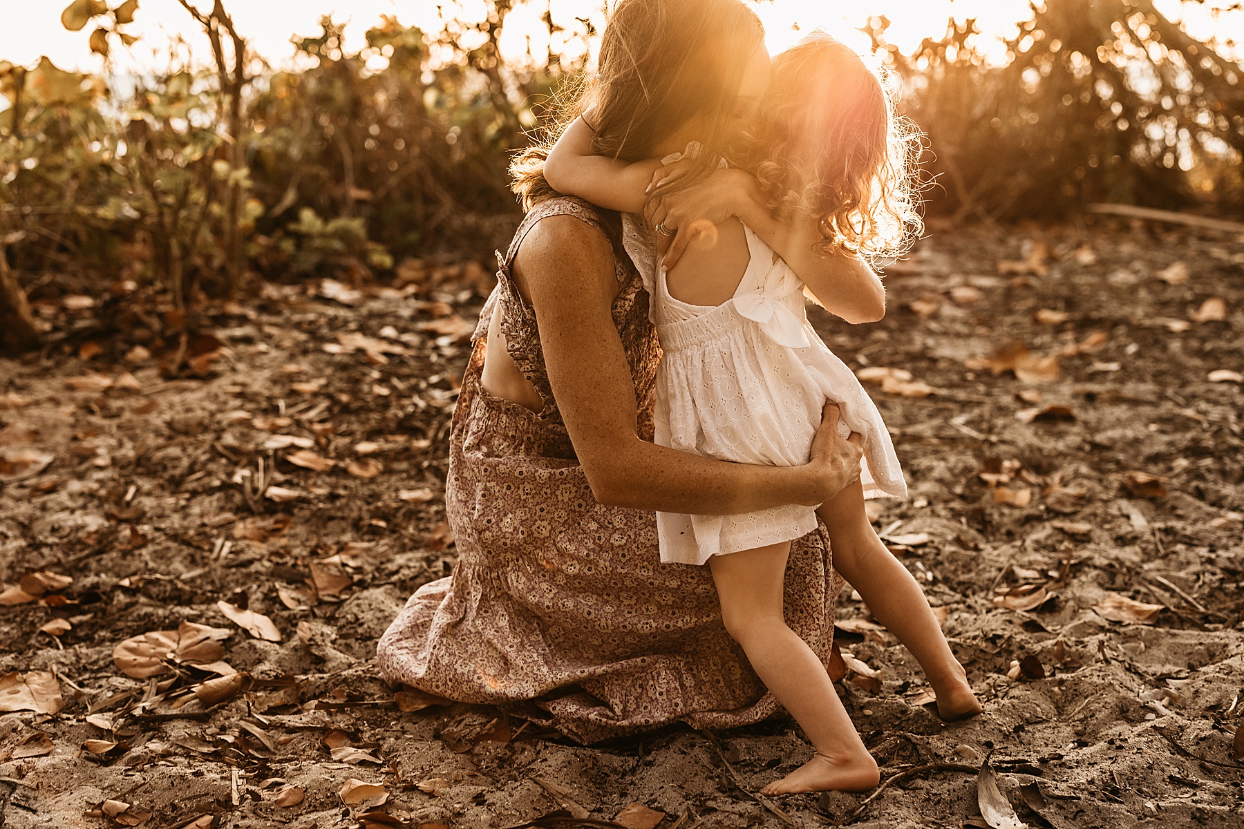 woman holding little girl at sunset on the beach in Wiggins Pass Naples