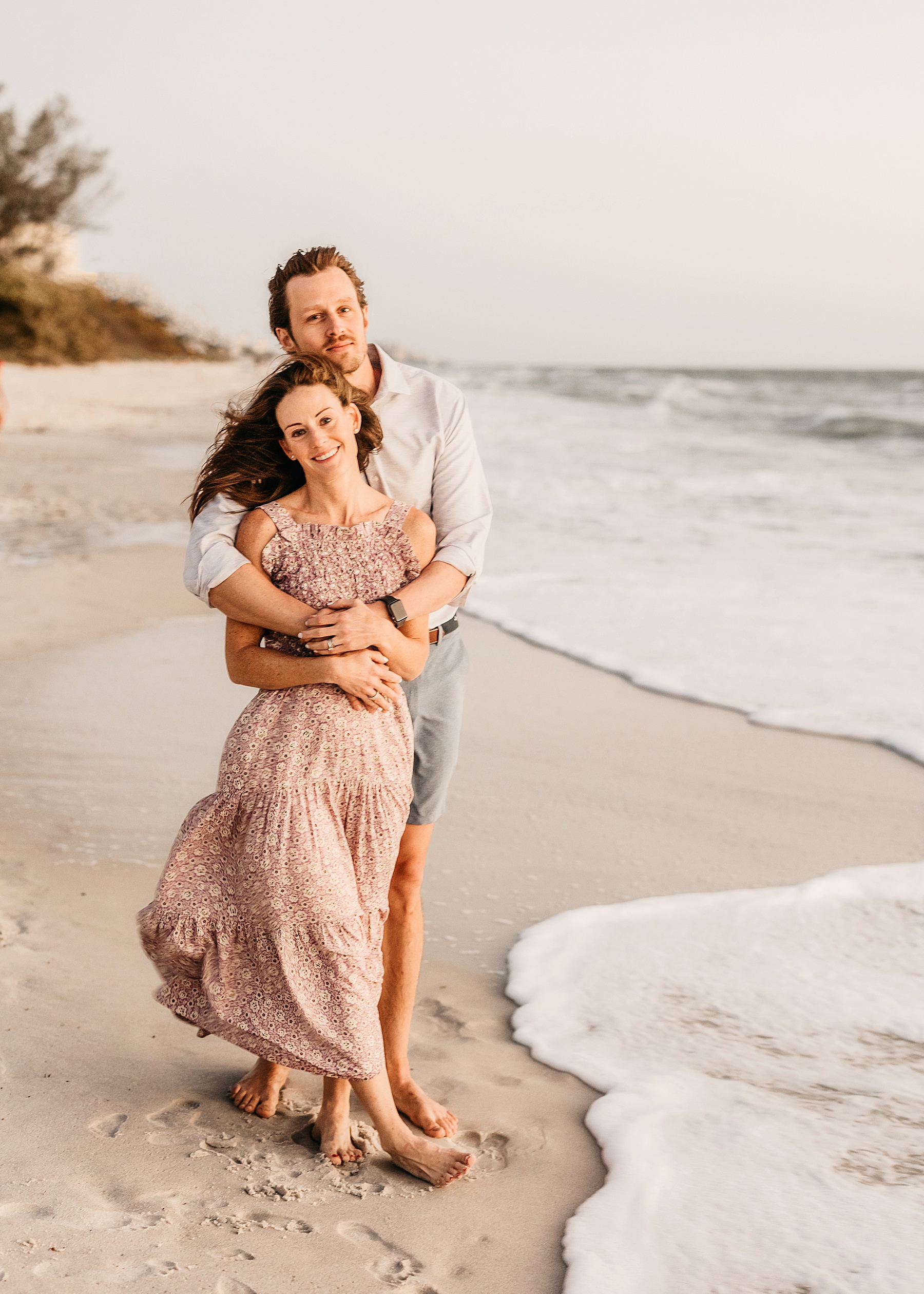 man and woman standing together on the beach at wiggins pass at sunset