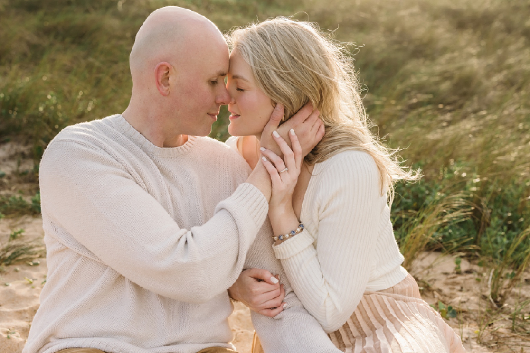 light and airy engagement portrait of couple on the beach at sunrise