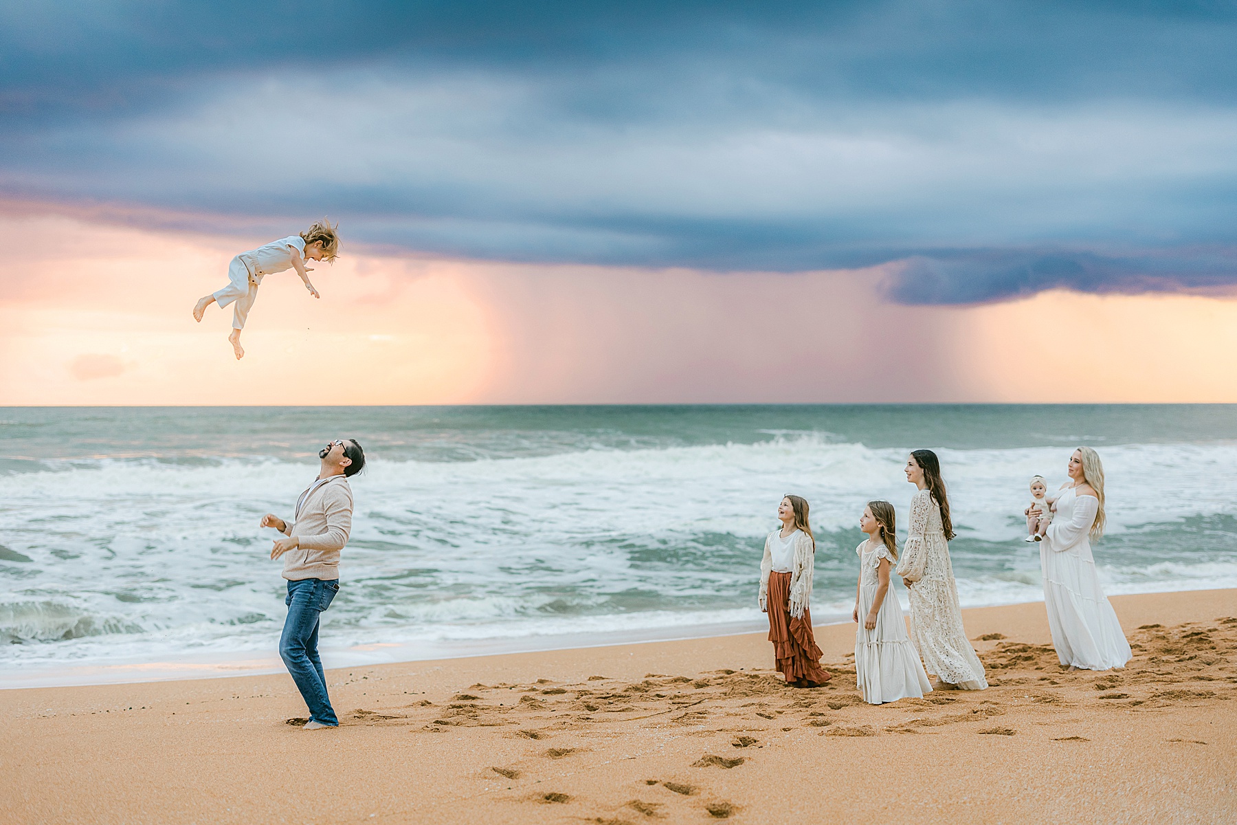 family playing against a colorful stormy pastel sky at sunrise in st. augustine beach florida