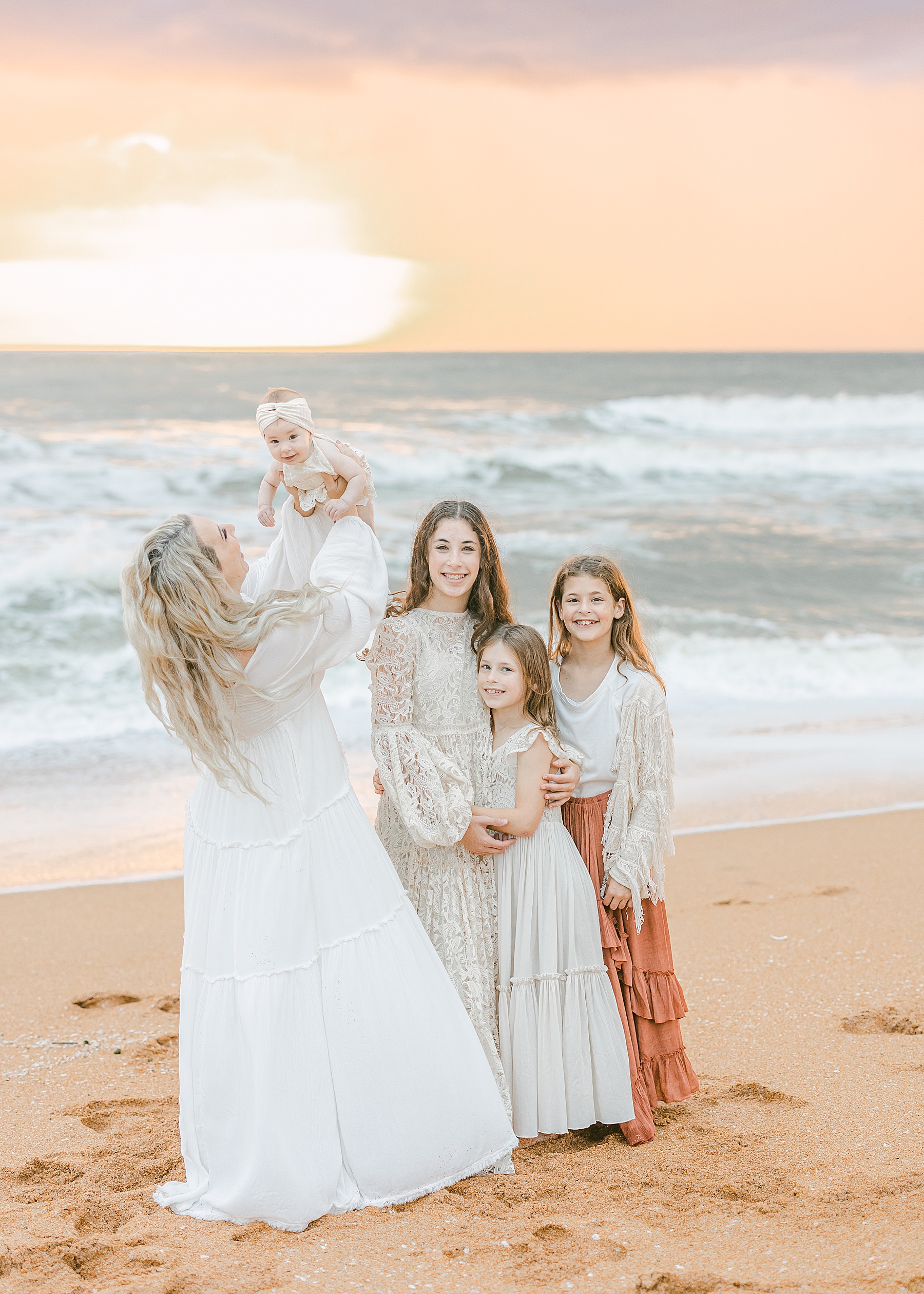 family dressed for beach portraits in white and neutral colors on the beach at sunrise 
