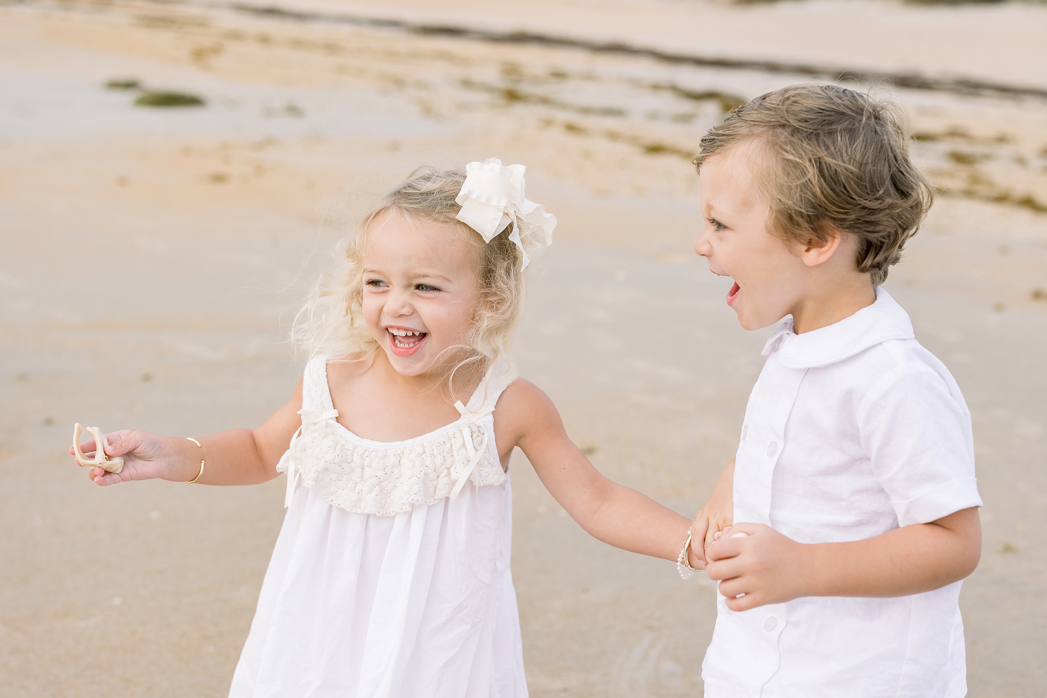 little blond-haired girl in white dress holding little boys hand