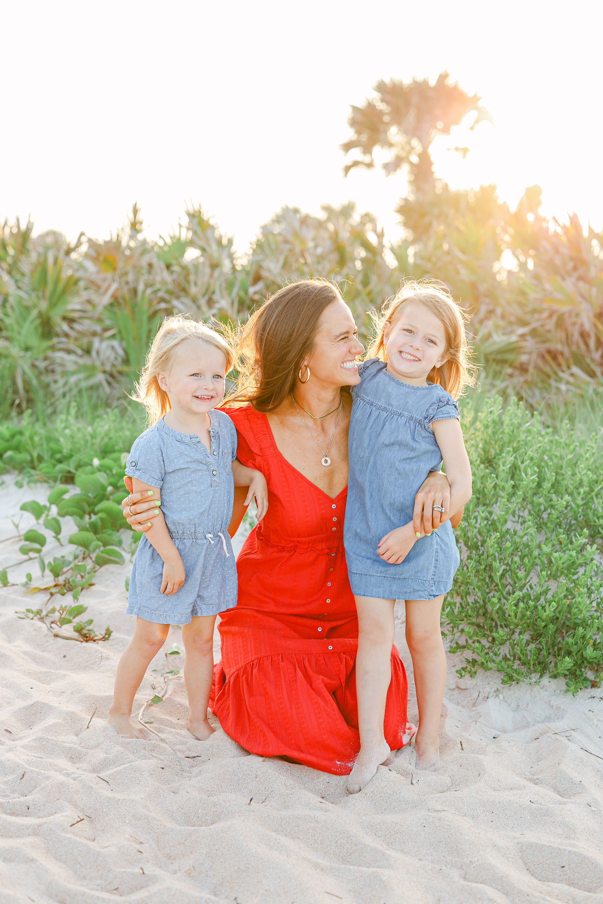 Woman in red dress holding her children on the beach