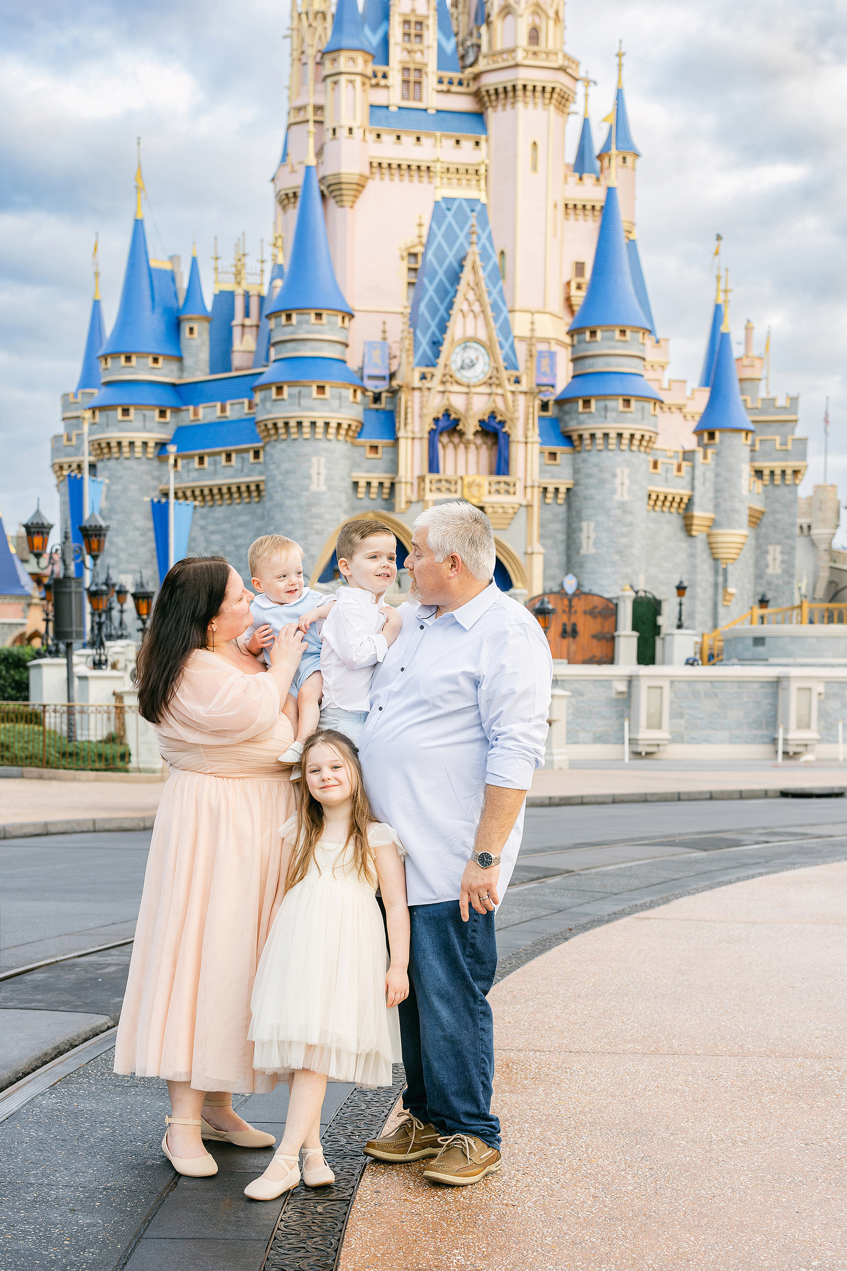 A family laughs together in front of Cinderella's Castle at the Magic Kingdom.