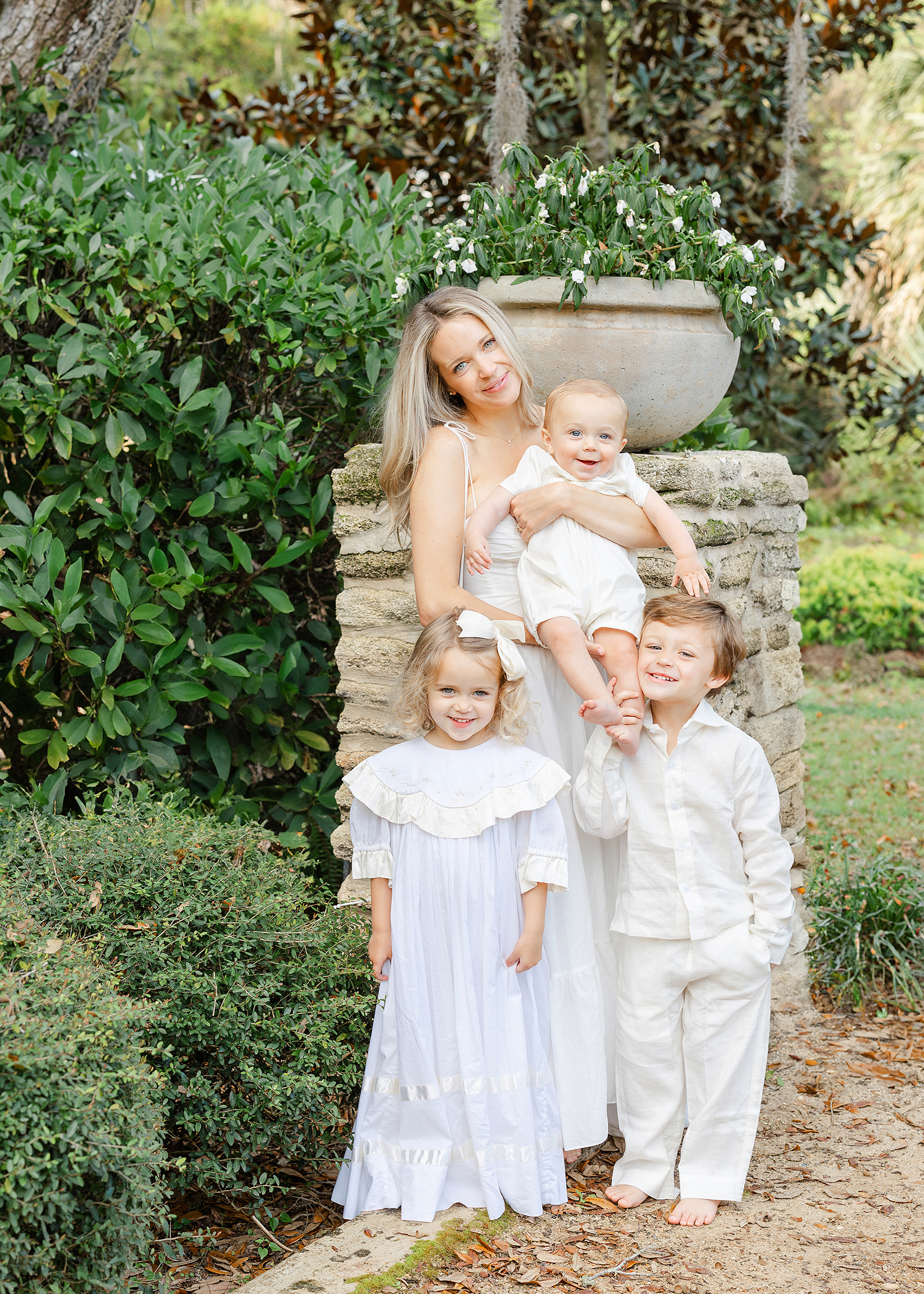 A spring portrait of a woman with her children all dressed in white in the gardens.
