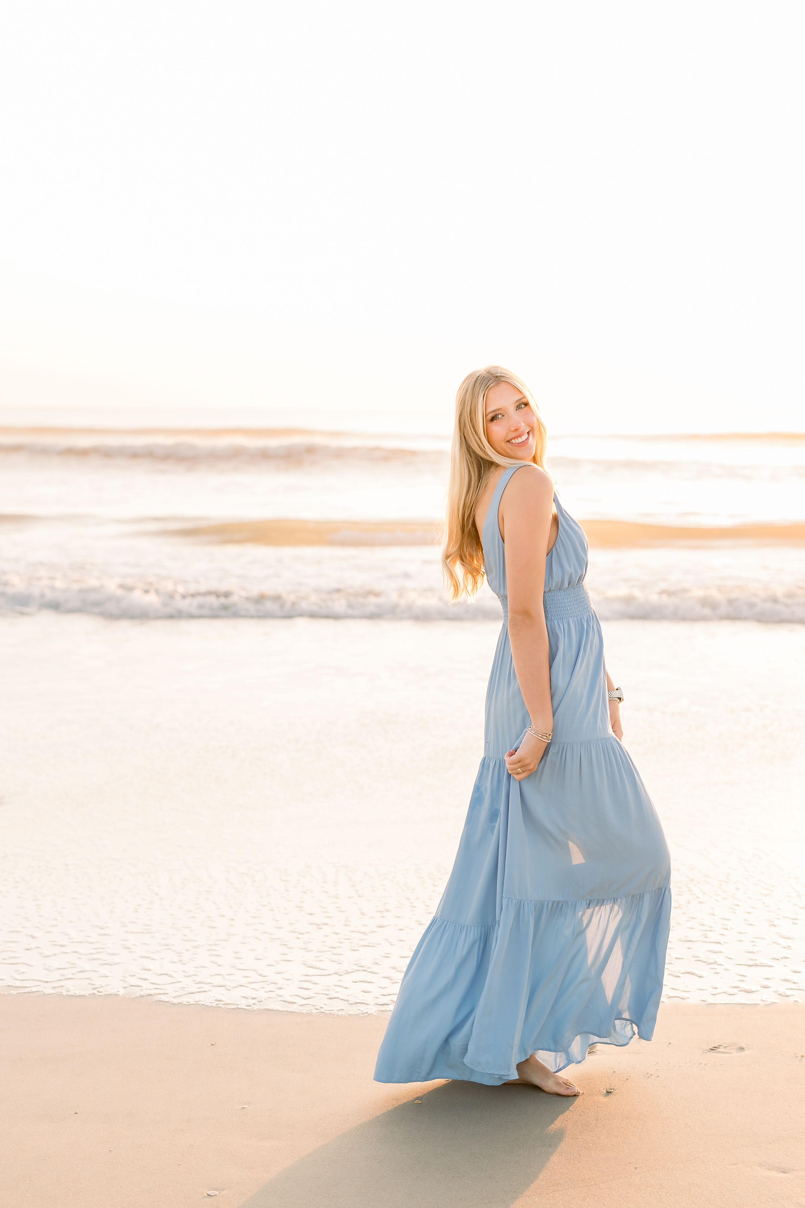 A light and airy sunrise portrait of a grad in a blue dress on St. Augustine Beach.
