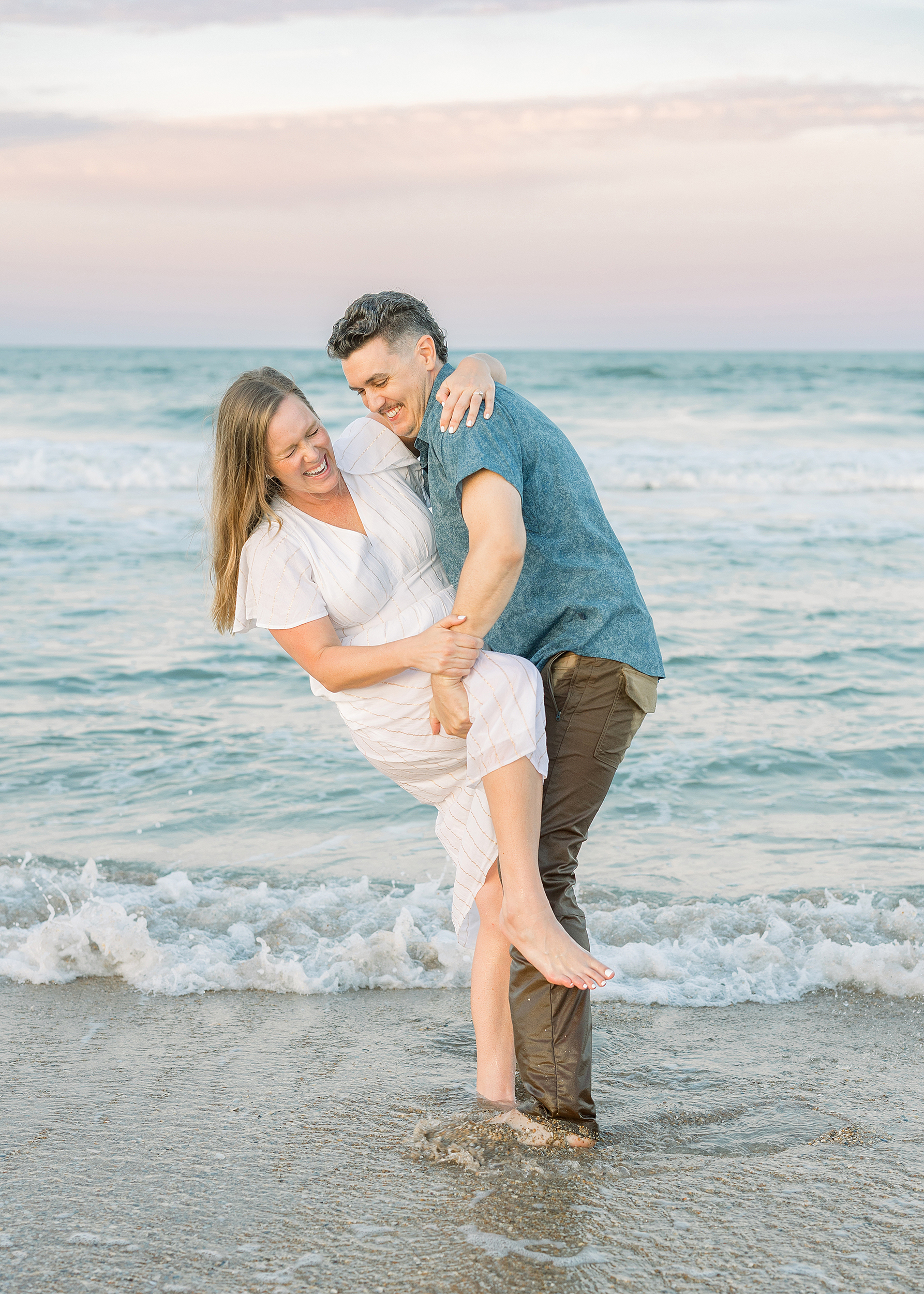 A colorful sunset engagement portrait of a man and woman on St. Augustine Beach at sunset.