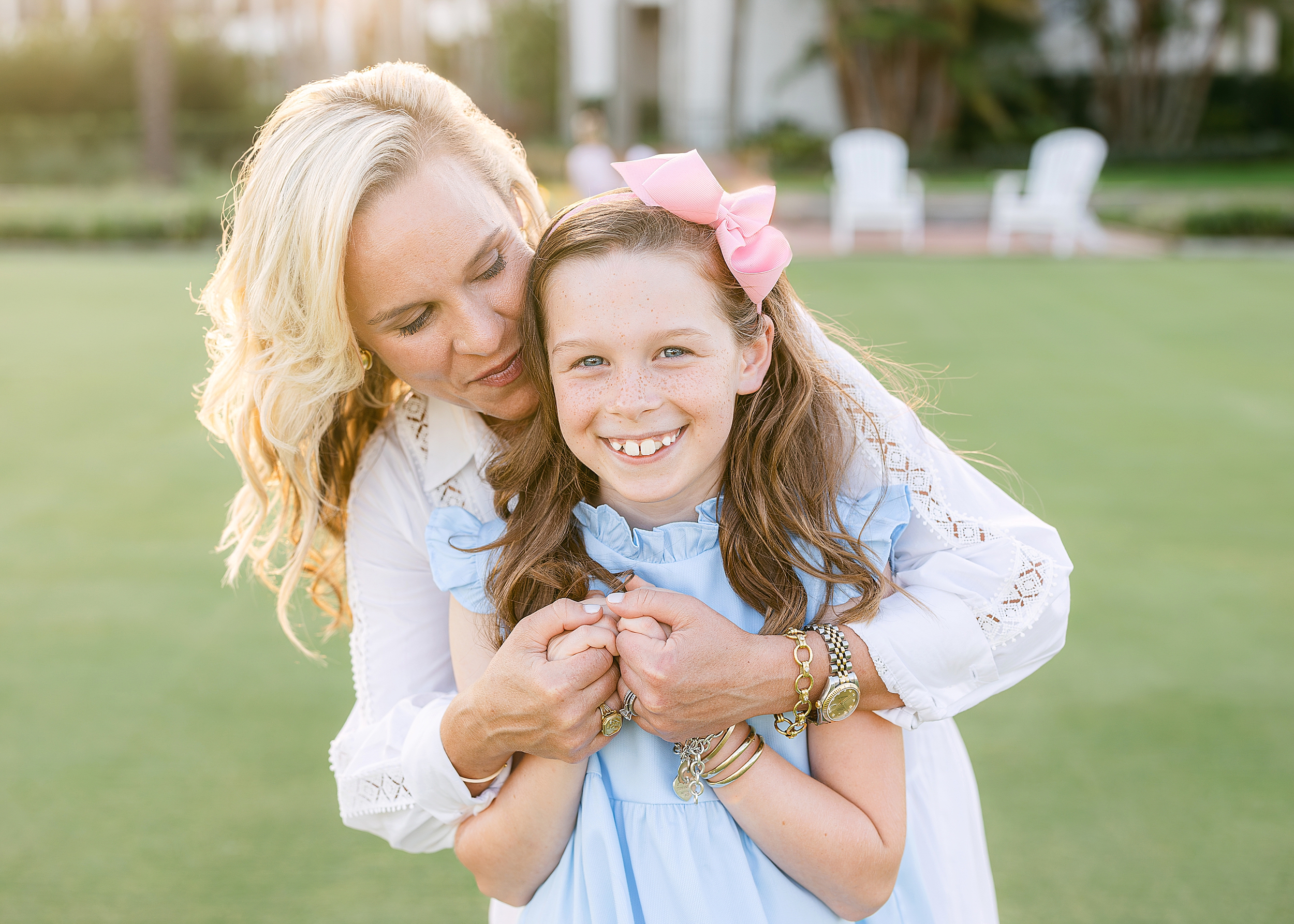 A blonde woman and her daughter embrace at sunset on the golf course at Ponte Vedra Inn and Club.