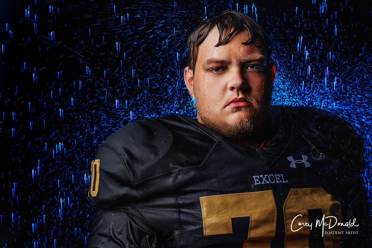 Football player in a wet jersey stands against a dark, rainy background.