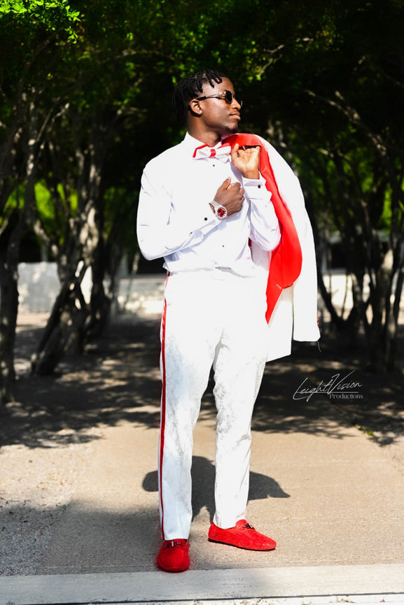 A man wearing a crisp white suit and eye-catching red shoes, presenting a unique and fashionable look.