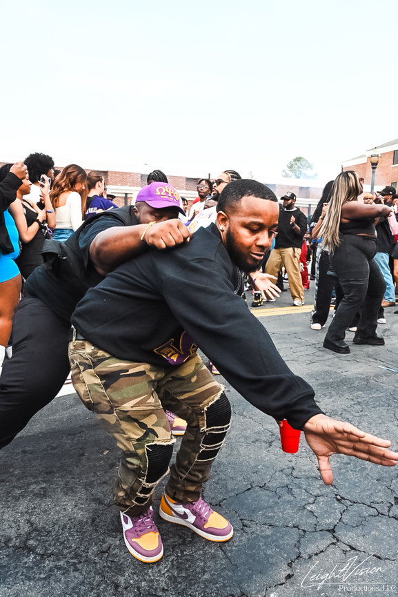 A man grips another man's leg as they engage in a lively dance together, showcasing their joyful movement.
