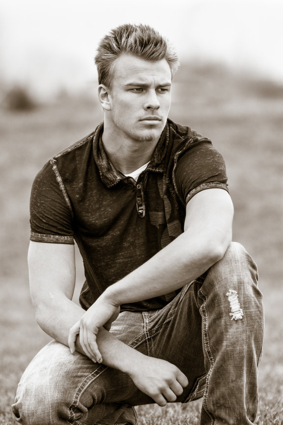 Black and white senior year photo of football player guy in jeans looking serious. Meridian, Idaho