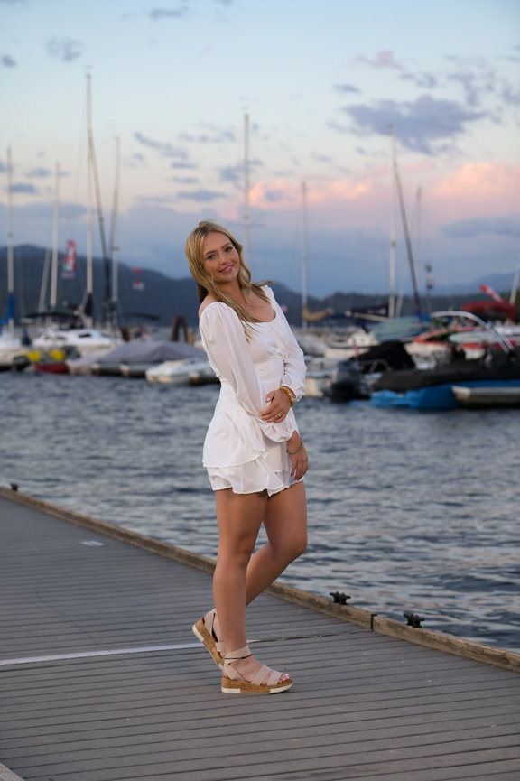 Senior year girl with a white sundress at sunset on a dock in McCall, Idhao
