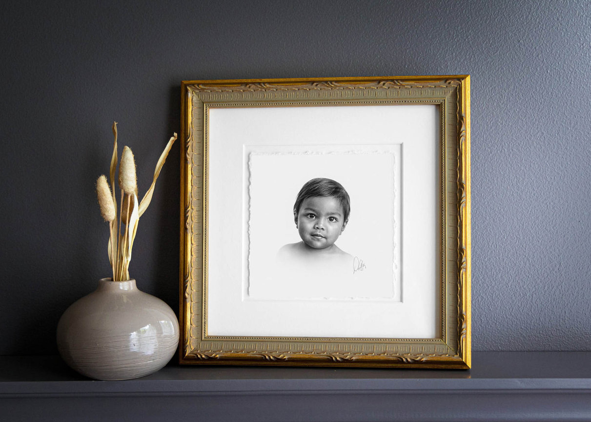 Fine art children’s portrait in charcoal, with a soft background and thoughtful gaze.