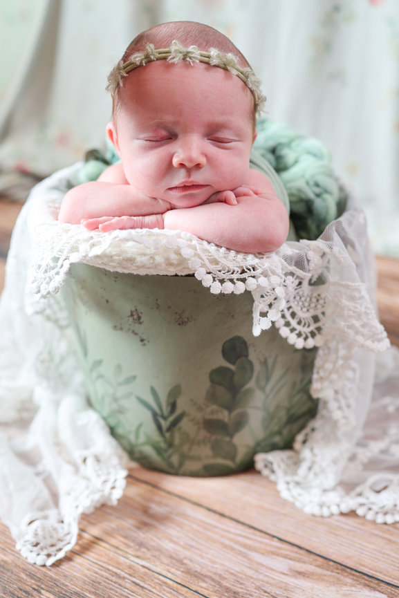 Sleeping newborn posed in a vintage bucket with lace blanket