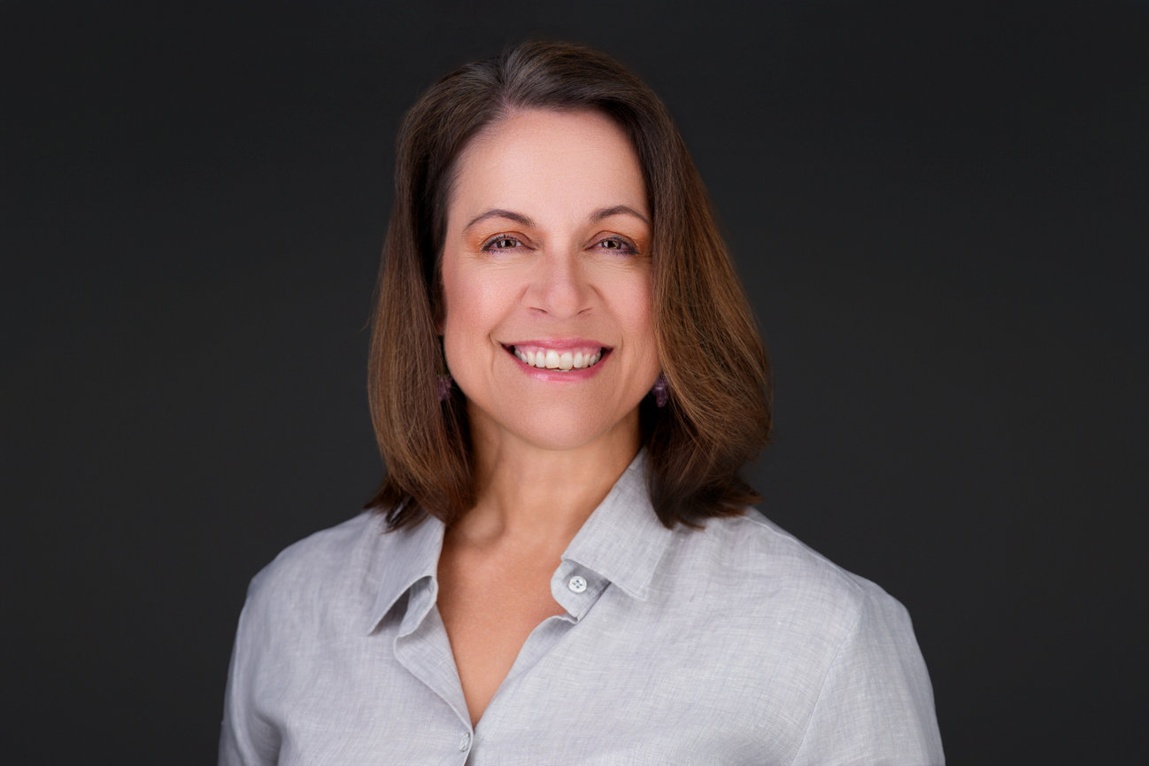 Smiling woman in light gray blouse in professional studio headshot, captured by DFW personal branding photographer