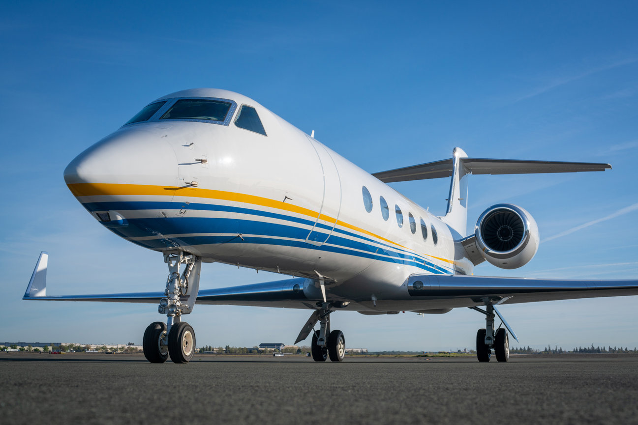 Private jet on runway under clear blue sky.