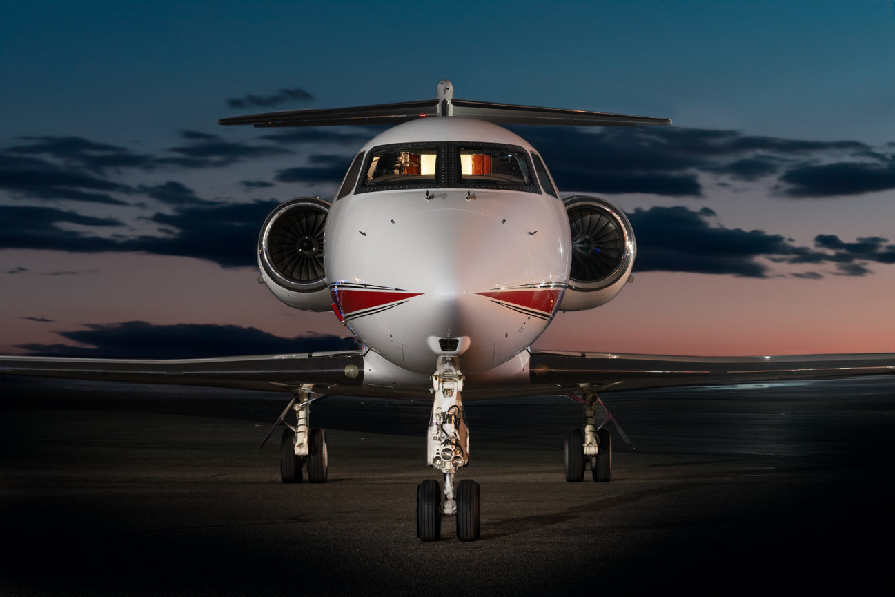 Private jet front view on a runway at dusk, with a darkening sky.