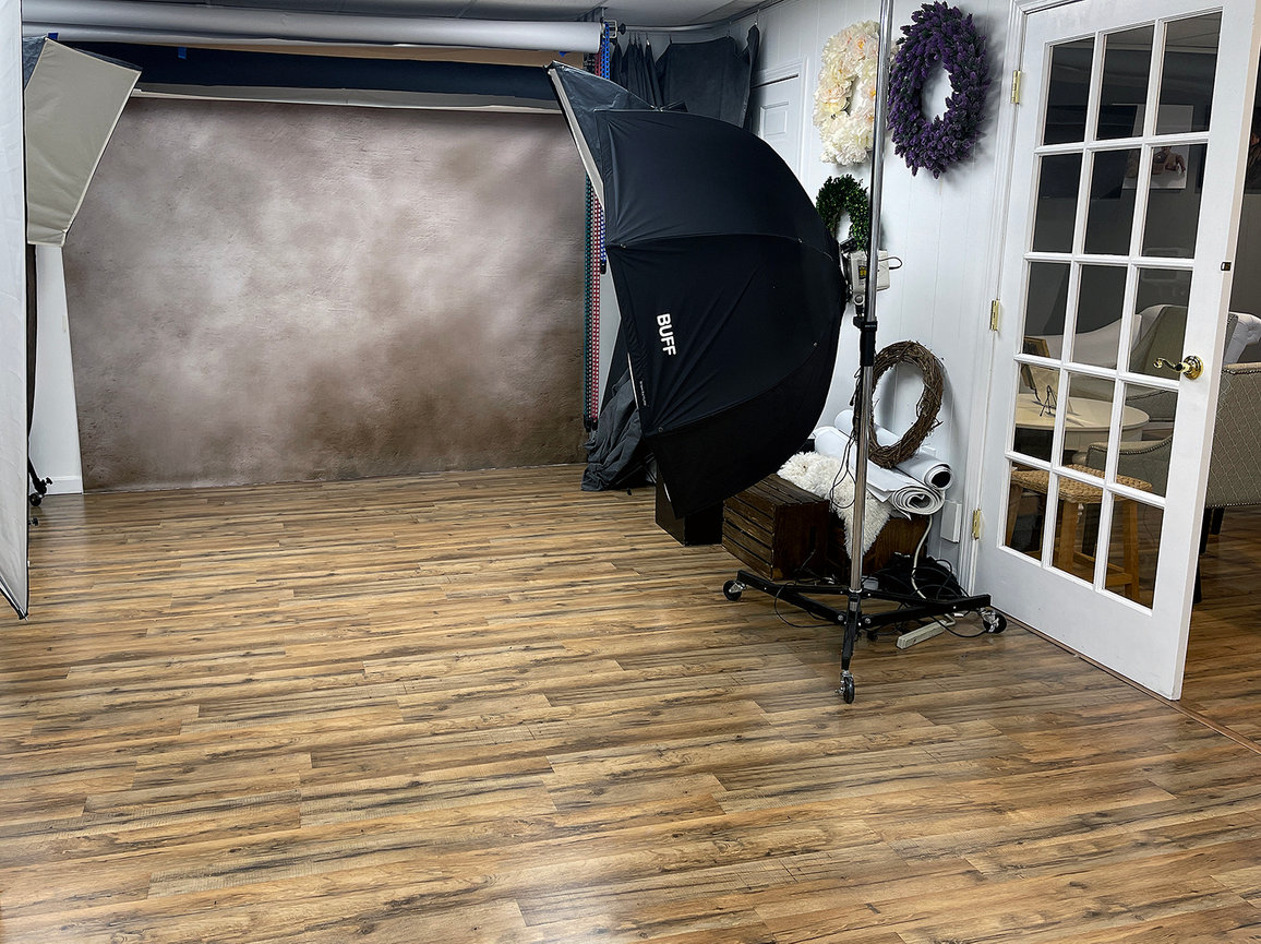 Paula Swift Photography studio setup with softbox lights, wooden floor, and a neutral backdrop in Sudbury, MA.