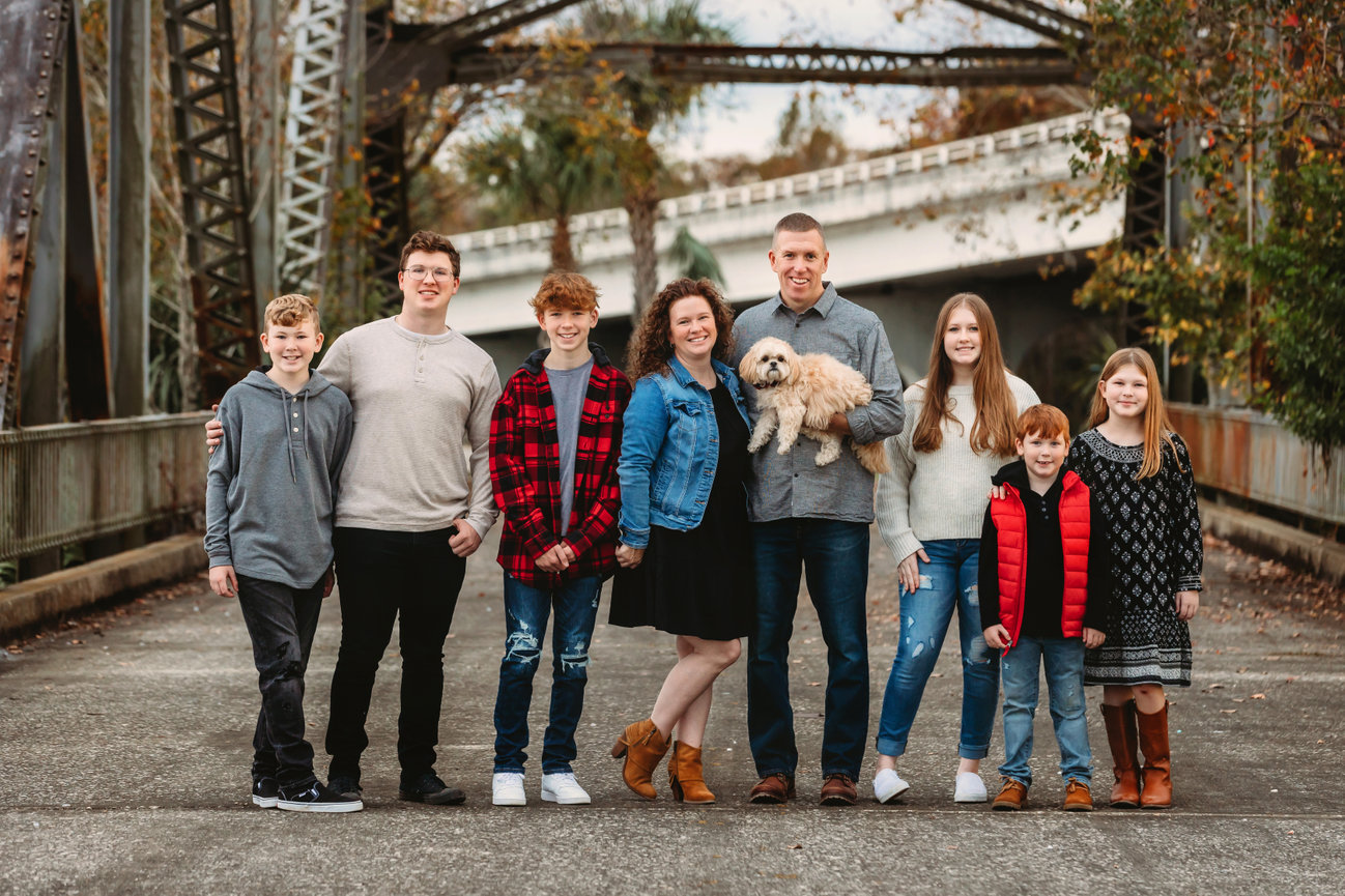 Family with 6 kids and dog are all smiles on Lake Monroe Bridge in Sanford Florida.
